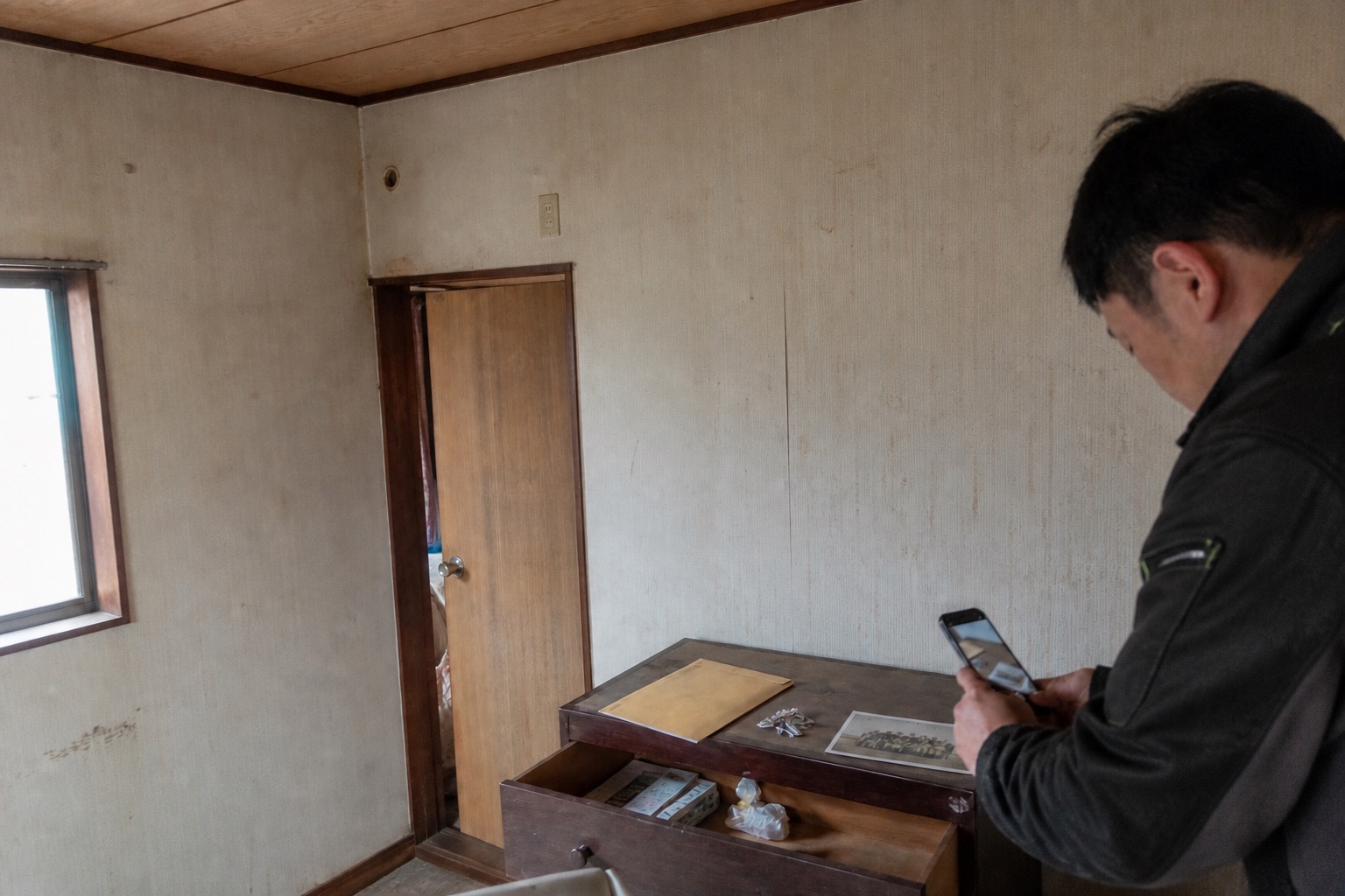 古い家の室内で、見つかった鍵や写真を処分前に記録する様子